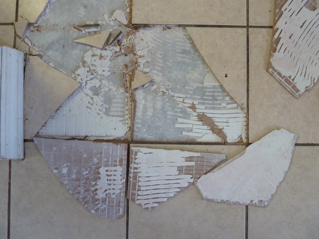 Broken and removed ceramic floor tile exposing mortar thinset mortar failure ceramic tile corrugated
