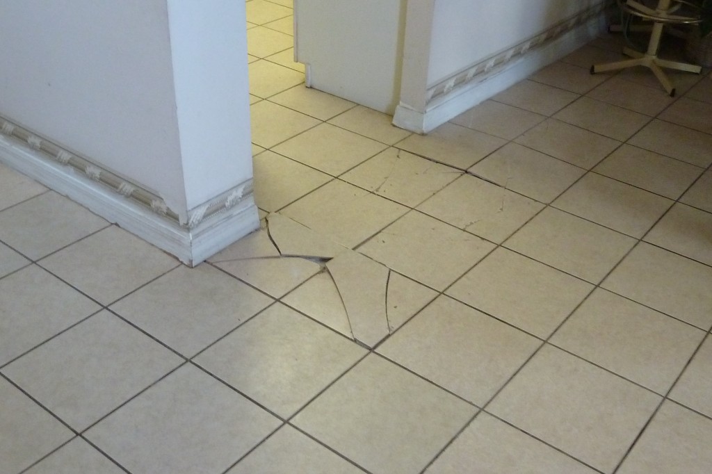 Tented and cracked ceramic floor tiles Tented and cracked ceramic floor tiles installed with thinset mortar over concrete slab on grade